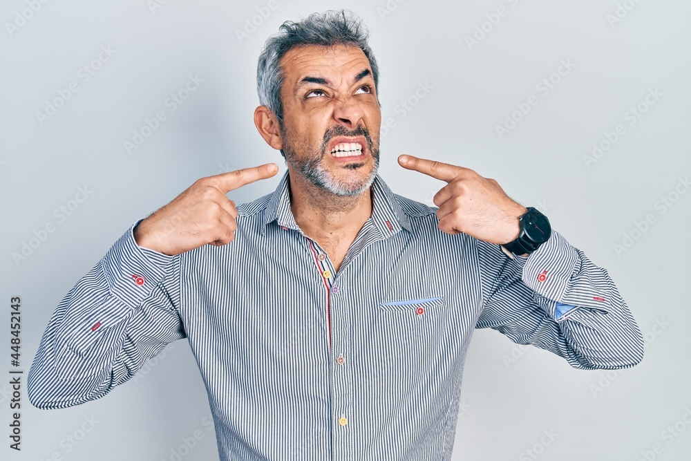 Handsome middle age man with grey hair pointing mouth with fingers angry and mad screaming frustrated and furious, shouting with anger looking up. Handsome middle age man with grey hair pointing mouth with fingers angry and mad screaming frustrated and furious, shouting with anger looking up.