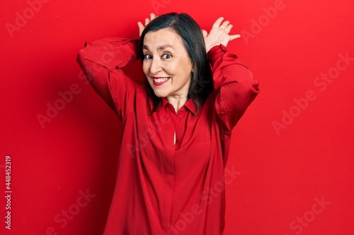 Middle age hispanic woman wearing casual clothes doing bunny ears gesture with hands palms looking cynical and skeptical. easter rabbit concept.