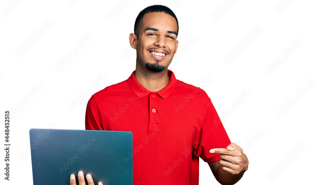Young african american man working using computer laptop smiling happy pointing with hand and finger Young african american man working using computer laptop smiling happy pointing with hand and finger