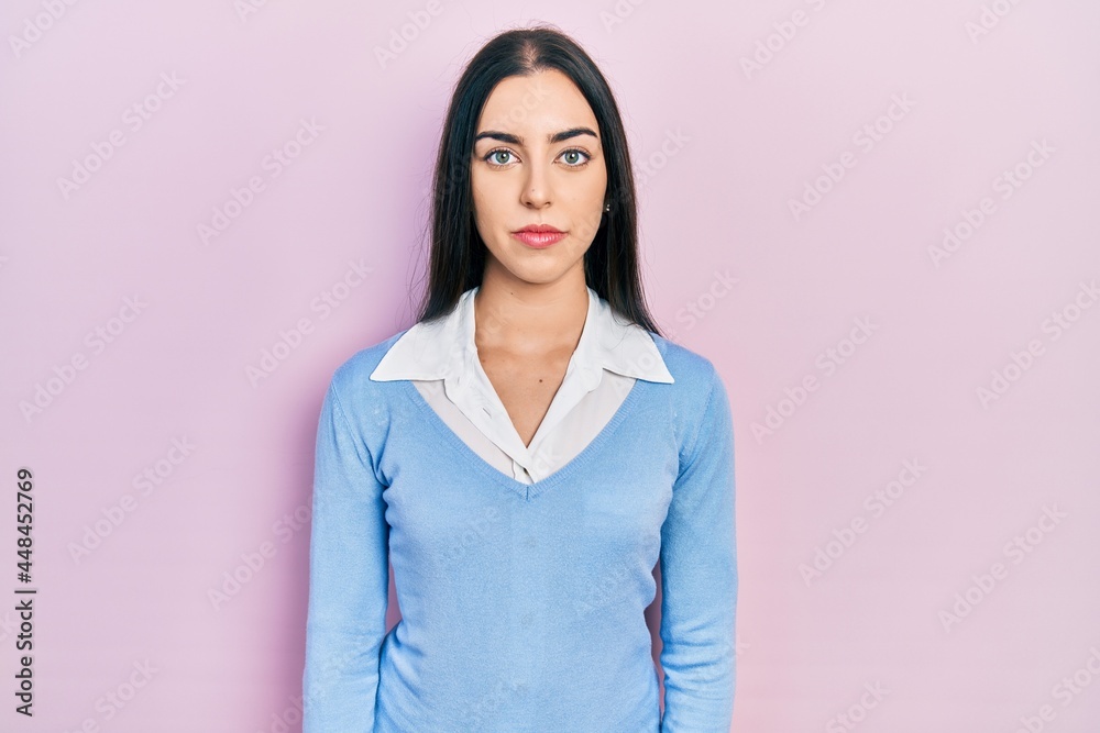 Beautiful woman with blue eyes standing over pink background relaxed with serious expression on face. simple and natural looking at the camera. Beautiful woman with blue eyes standing over pink background relaxed with serious expression on face. simple and natural looking at the camera.