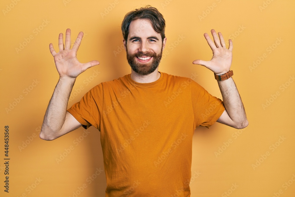 Caucasian man with beard wearing casual yellow t shirt showing and pointing up with fingers number ten while smiling confident and happy. Caucasian man with beard wearing casual yellow t shirt showing and pointing up with fingers number ten while smiling confident and happy.