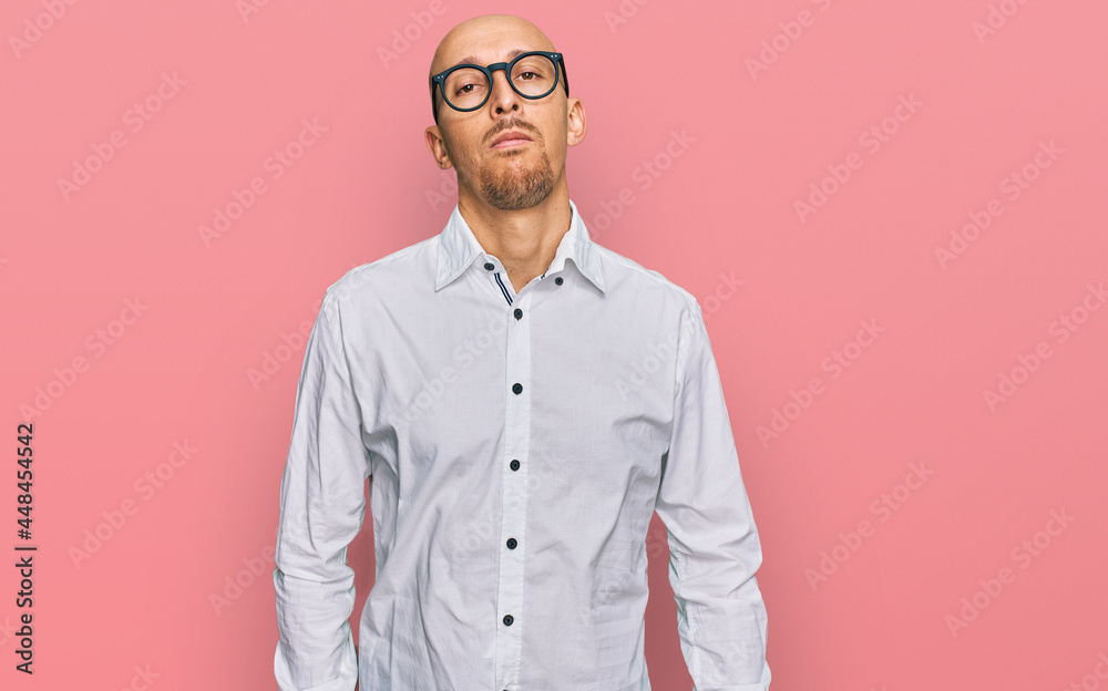 Bald man with beard wearing business shirt and glasses relaxed with serious expression on face. simple and natural looking at the camera. Bald man with beard wearing business shirt and glasses relaxed with serious expression on face. simple and natural looking at the camera.