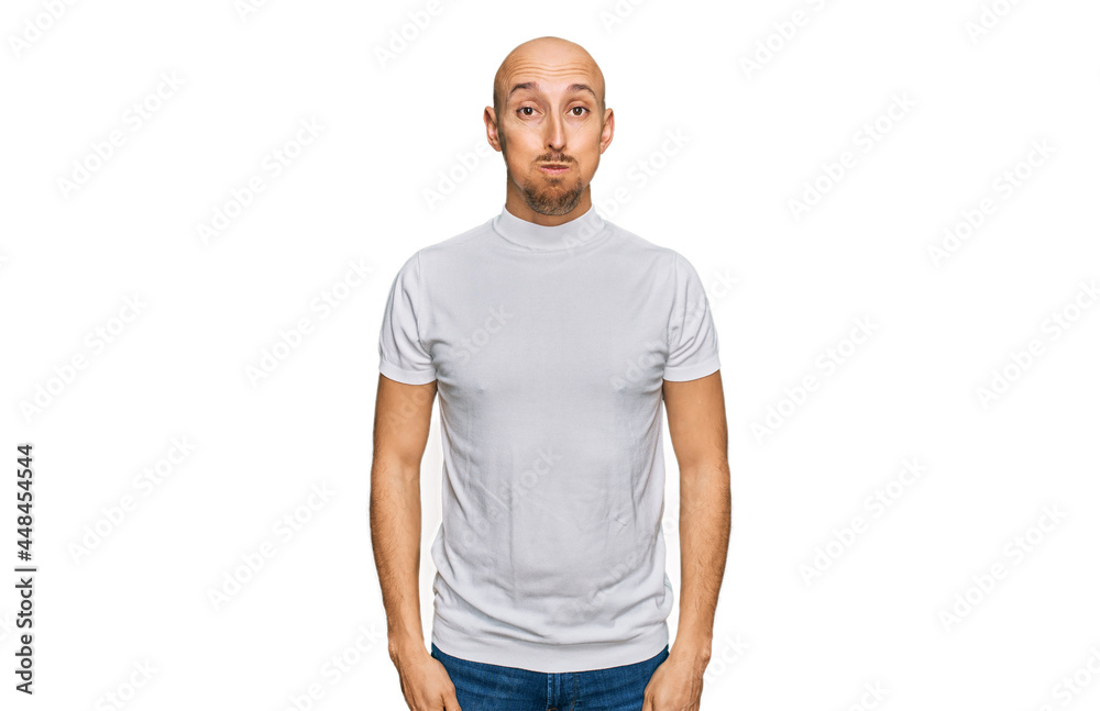 Bald man with beard wearing casual white t shirt puffing cheeks with funny face. mouth inflated with air, crazy expression. Bald man with beard wearing casual white t shirt puffing cheeks with funny face. mouth inflated with air, crazy expression.