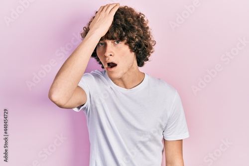 Handsome young man wearing casual white t shirt surprised with hand on head for mistake, remember error. forgot, bad memory concept.