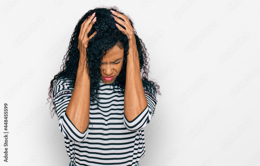 Middle age african american woman wearing casual clothes suffering from headache desperate and stressed because pain and migraine. hands on head. Middle age african american woman wearing casual clothes suffering from headache desperate and stressed because pain and migraine. hands on head.