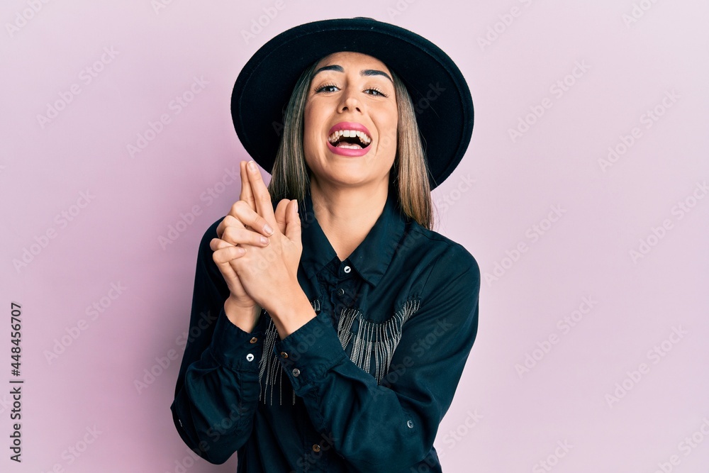 Young hispanic woman wearing cowgirl style doing pistol gesture with hands smiling and laughing hard out loud because funny crazy joke. Young hispanic woman wearing cowgirl style doing pistol gesture with hands smiling and laughing hard out loud because funny crazy joke.