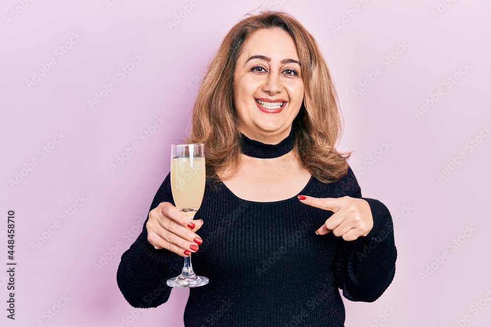 Middle age caucasian woman drinking glass of champagne smiling happy pointing with hand and finger Middle age caucasian woman drinking glass of champagne smiling happy pointing with hand and finger