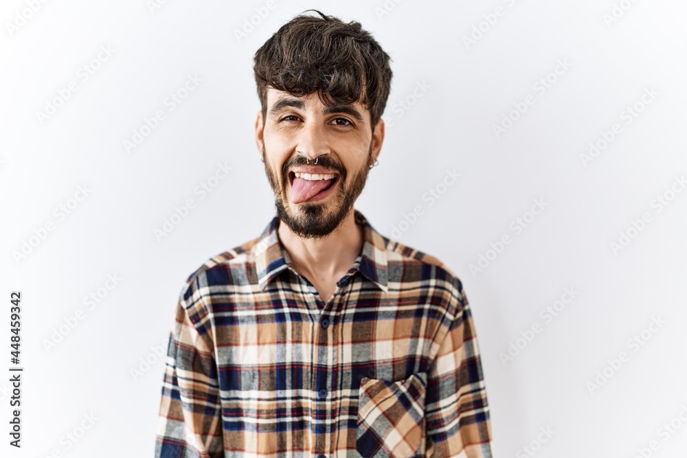 Hispanic man with beard standing over isolated background sticking tongue out happy with funny expression. emotion concept. Hispanic man with beard standing over isolated background sticking tongue out happy with funny expression. emotion concept.