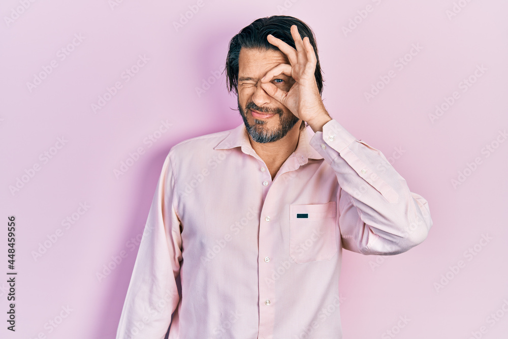 Middle age caucasian man wearing casual clothes doing ok gesture with hand smiling, eye looking through fingers with happy face. Middle age caucasian man wearing casual clothes doing ok gesture with hand smiling, eye looking through fingers with happy face.