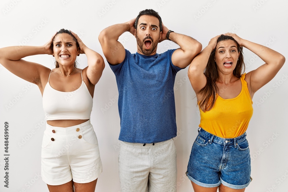 Group of young hispanic people standing over isolated background crazy and scared with hands on head, afraid and surprised of shock with open mouth