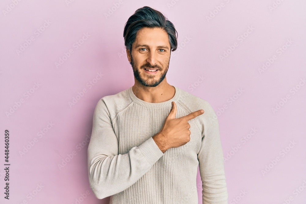Young hispanic man wearing casual winter sweater cheerful with a smile of face pointing with hand and finger up to the side with happy and natural expression on face Young hispanic man wearing casual winter sweater cheerful with a smile of face pointing with hand and finger up to the side with happy and natural expression on face