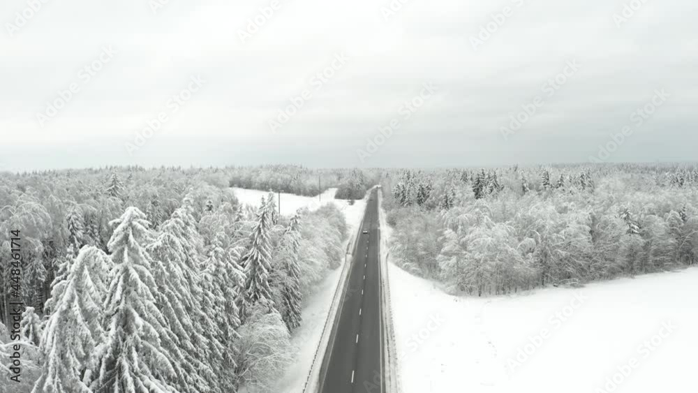 Aerial bird-eye view on winter freeway road. Asphalt road in the frozen forest.
