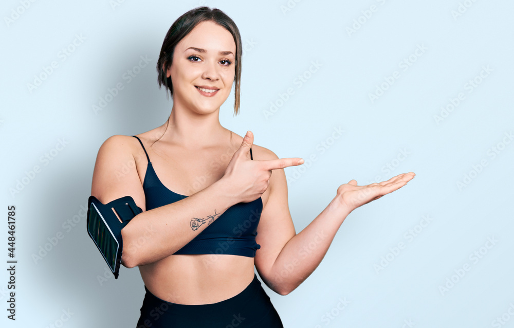 Young hispanic woman wearing sportswear amazed and smiling to the camera while presenting with hand and pointing with finger. Young hispanic woman wearing sportswear amazed and smiling to the camera while presenting with hand and pointing with finger.