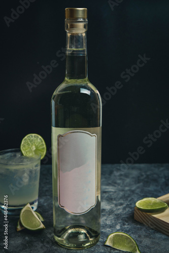 Bottle of vodka, white wine, pisco on black background. Drink with lime on black marble. White label without mark.