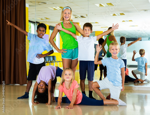 Cheerful children having fun in choreography class, posing with woman trainer