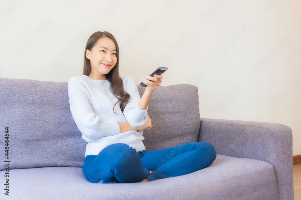 Portrait beautiful young asian woman use remote for change channel Portrait beautiful young asian woman use remote for change channel