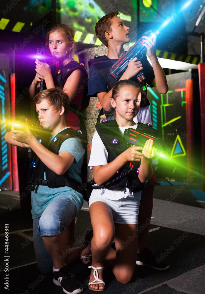 Cheerful teen girls and boys with laser pistols posing together in dark laser  tag labyrinth.. Stock Photo | Adobe Stock