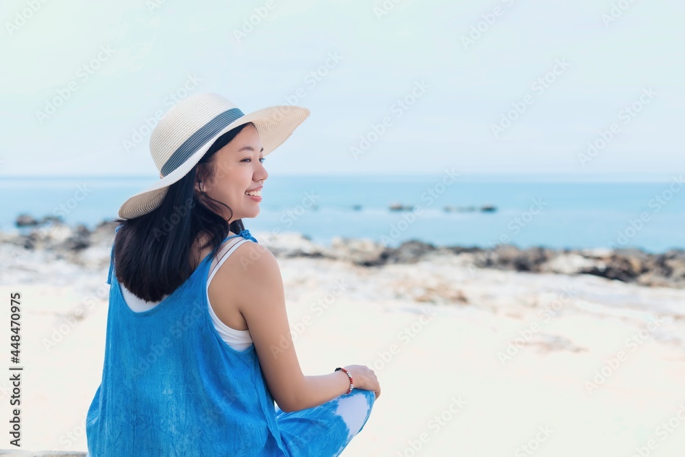 Asian traveler woman sitting and relaxing at the beach by the sea background.Concept of happy travel on vacation weekend. Asian traveler woman sitting and relaxing at the beach by the sea background.Concept of happy travel on vacation weekend.