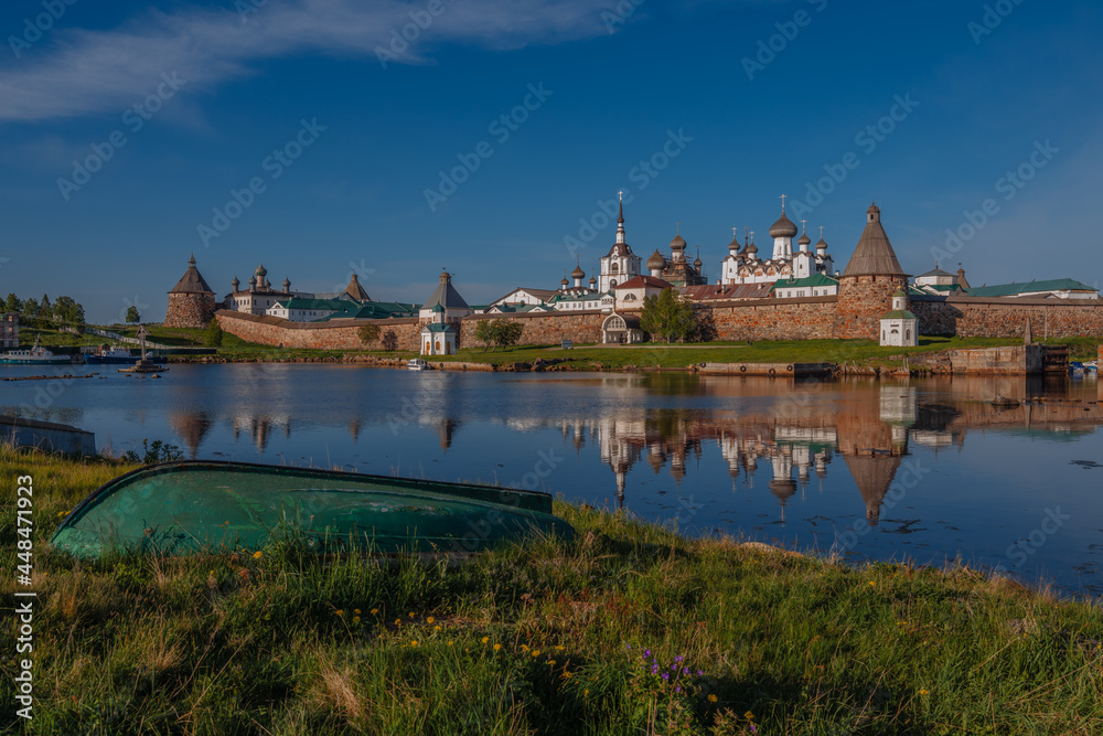 View of the Spaso-Preobrazhensky Solovetsky Monastery on the shore of the White Sea Bay and the old boat in the foreground on a cloudless summer day, Solovetsky Island, Arkhangelsk region, Russia