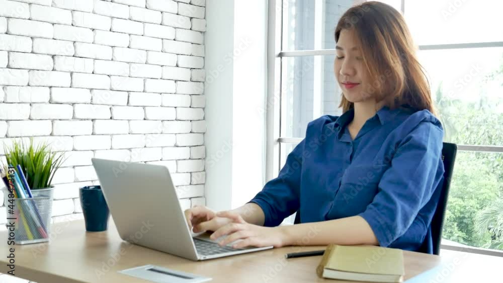 Happiness Asian Woman working from home using laptop online meeting in home office. Happy relax time asian business woman typing keyboard use notebook laptop Smiling, laughing at home office. Happiness Asian Woman working from home using laptop online meeting in home office. Happy relax time asian business woman typing keyboard use notebook laptop Smiling, laughing at home office.