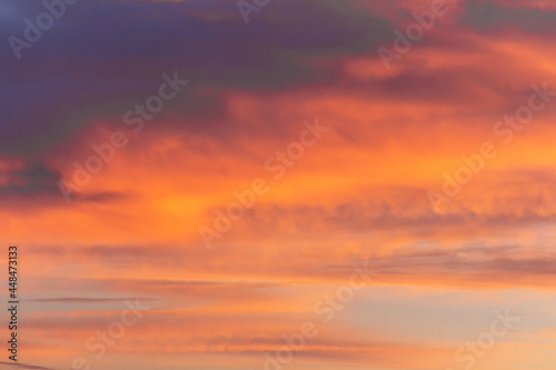 Colorful dramatic sky at sunset with layered rain clouds of purple and gold color © Volodya