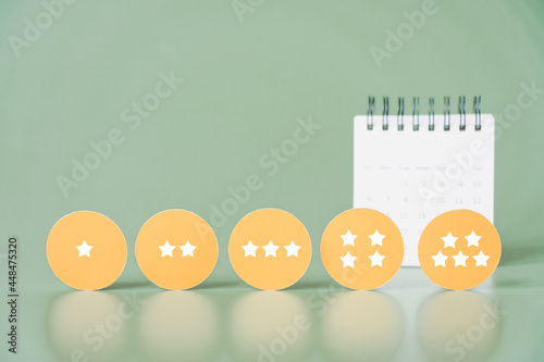 rating stars on yellow circle paper with blurred white calendar, ranking, survey, feedback, satisfaction, probation period