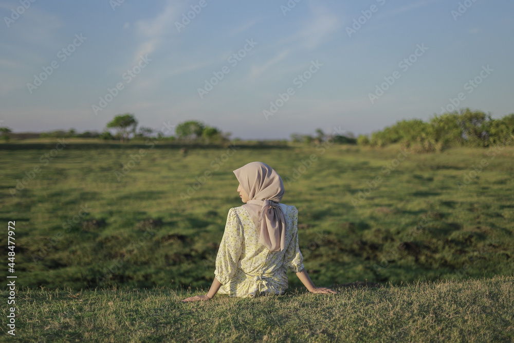 Woman with white dress enjoying the sunset on the grass. Summer vacation at Buffalo Village