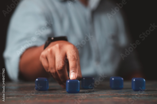 A businessman's hand points to an empty blue square block. The concept of pointing out a clear goal.
