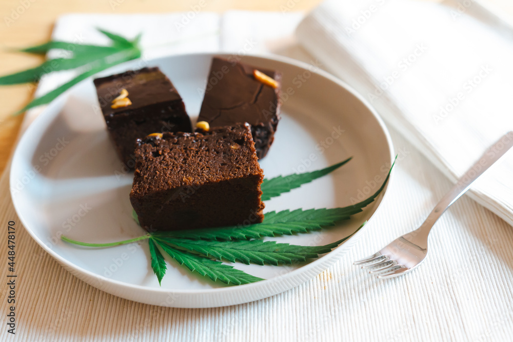 Homemade sweetmeat with marijuana or cannabis leaf on white plate. Alternative medicine concept.. Homemade sweetmeat with marijuana or cannabis leaf on white plate. Alternative medicine concept..