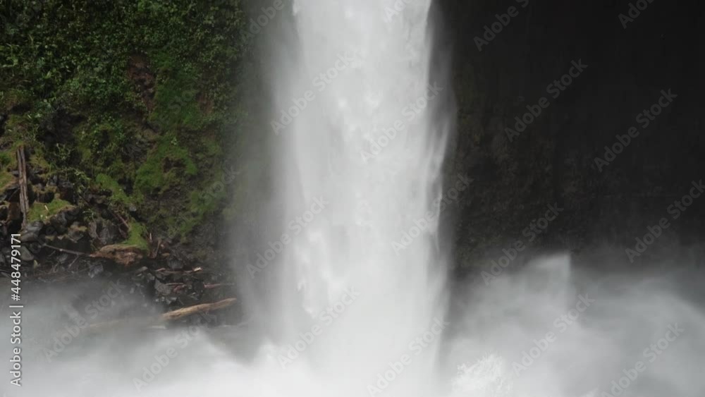 Slow motion shot panning up large jungle waterfall Costa Rica rainy season Slow motion shot panning up large jungle waterfall Costa Rica rainy season
