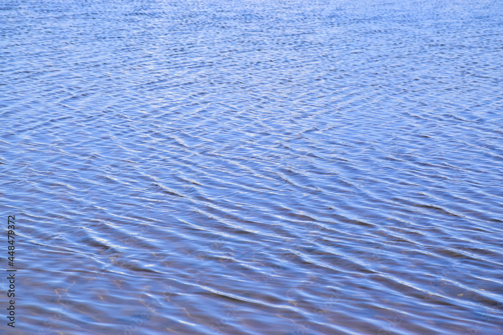 Day shot of a horizontal abstract seascape of dark blue sea with water ripple wave and reflection pattern background. Natural texture view with copy space for texting and designing in holiday concept