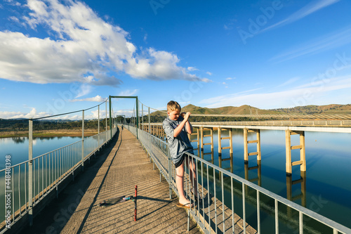 Boy climbing on railing of the rail trail bridge crossing of Lake Eildon at Bonnie Doon
