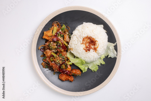 Chinese style Kung Pao Gong Bao Kung Po stair fried chicken with steamed rice lettuce on dark plate