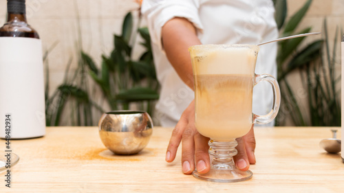 A man displaying a drink in a glass cup