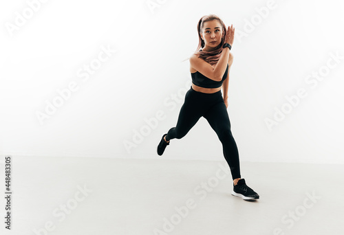 Muscular woman exercising in studio. Young female running forward.