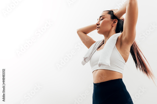 Fototapeta Naklejka Na Ścianę i Meble -  Exhausted woman with closed eyes and towel on neck relaxing after exercises
