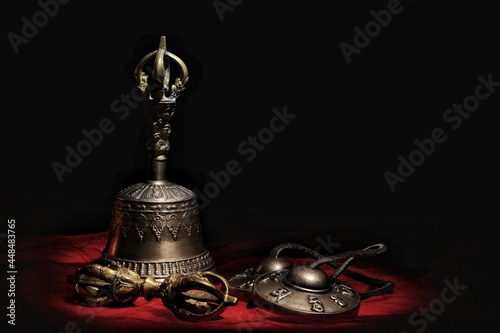 lying on a red fabric on a black background vajra and tingsha and ghanta Tibetan meditation bells photo
