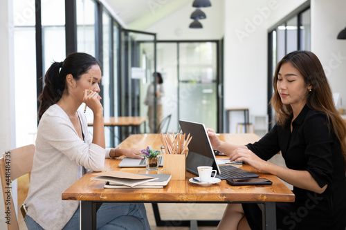 Two beautiful women colleagues working together in creative office.