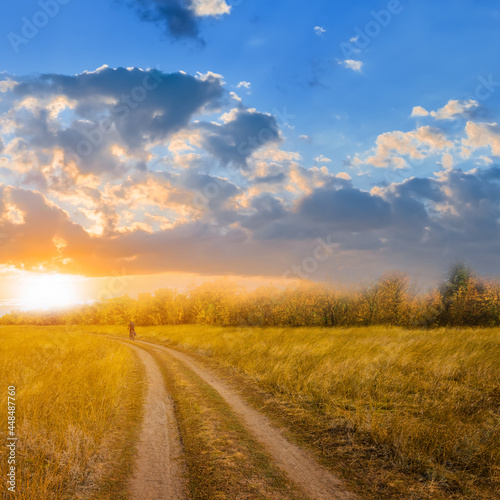 cyclist riding ground road among prairie at the sunset  natural travel background