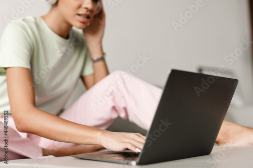 Young black woman in headphones using laptop while sitting on couch