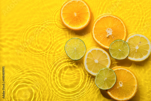 Fototapeta Naklejka Na Ścianę i Meble -  Citrus fruits in yellow water background with concentric circles and ripples. Refreshing summer concept, Copy space