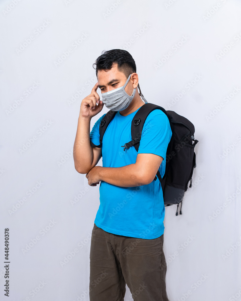 a man with black backpack wears a double mask. acting thinking about something. ready to go to traveling a man with black backpack wears a double mask. acting thinking about something. ready to go to traveling