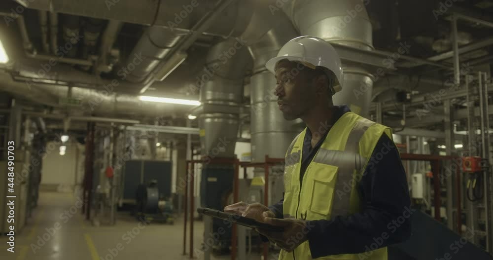 African american male engineer inspecting an industrial plant room African american male engineer inspecting an industrial plant room