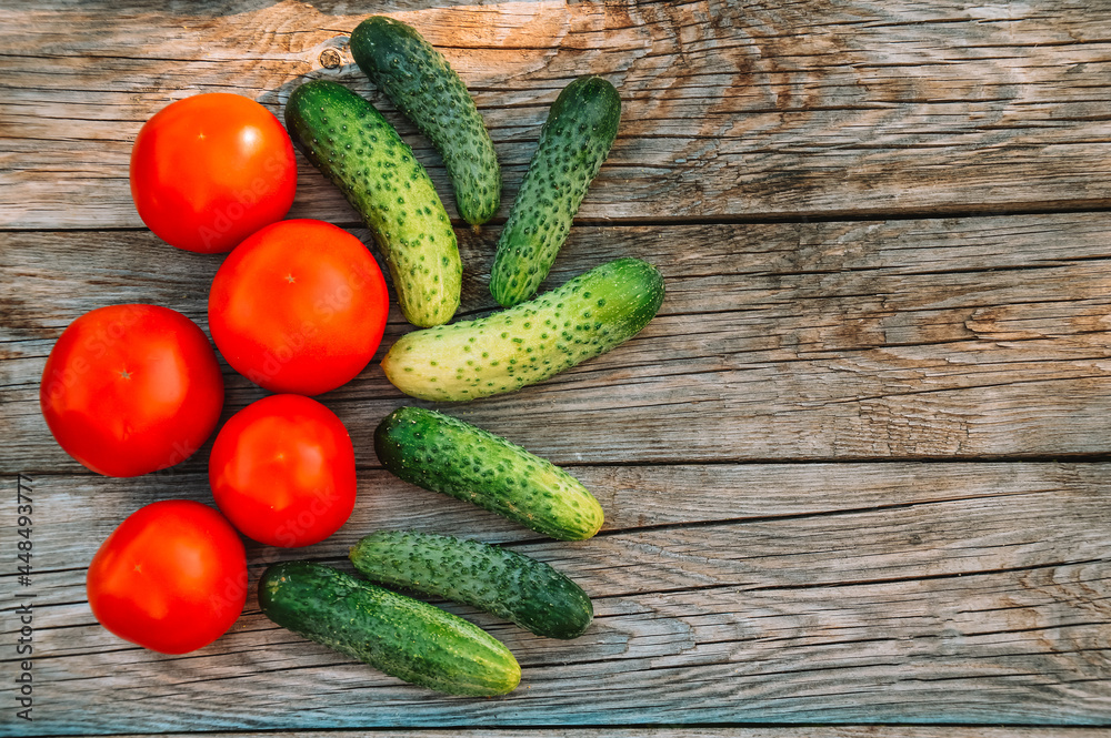 Cucumbers and tomatoes on a wooden background. Harvesting from the garden. Eco products. Farming Cucumbers and tomatoes on a wooden background. Harvesting from the garden. Eco products. Farming