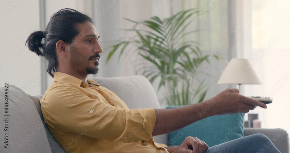 Obraz premium Man sitting on the couch and watching TV