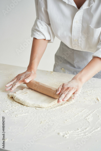 woman baker in working uniform rolls out dough © SHOTPRIME STUDIO