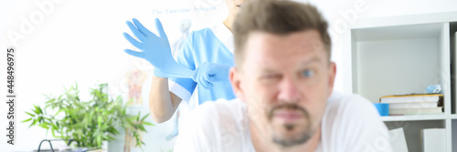 Tableau sur toile Doctor putting on protective glove for rectal examination of man
