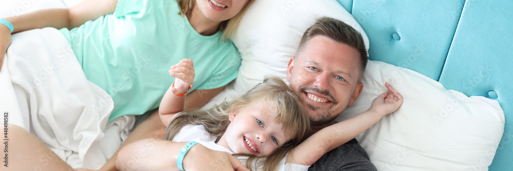 Young man and woman lying with little girl in bed Young man and woman lying with little girl in bed