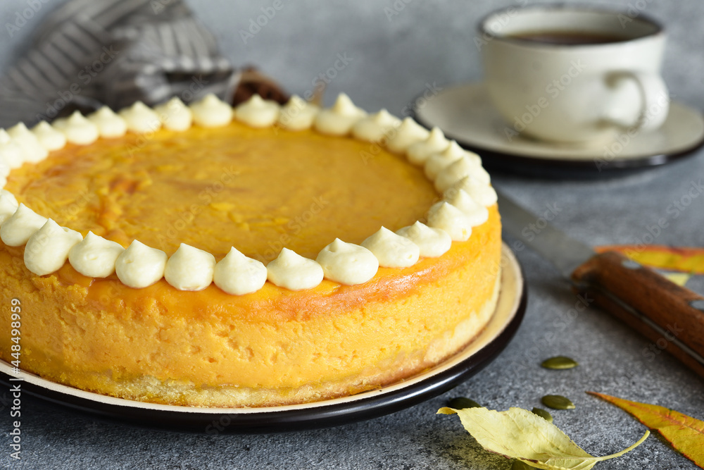 Delicate cheesecake with pumpkin on a wooden board on a concrete background. Delicate cheesecake with pumpkin on a wooden board on a concrete background.
