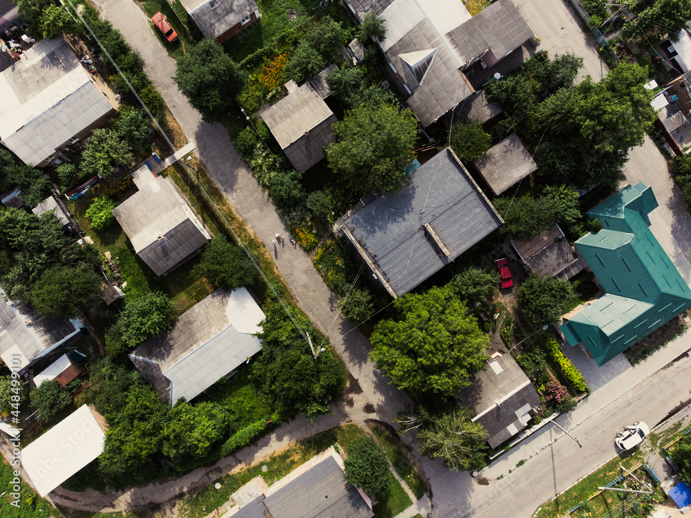 Aerial view of suburb of European city. Green neighbourhood on a sunny summer day. County living. Drone point of view